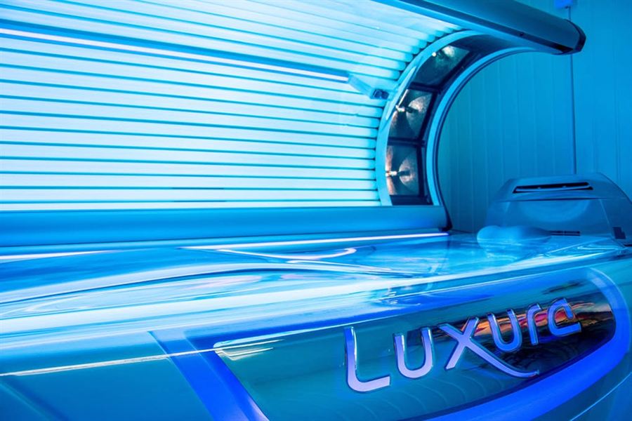 The Luxura stand-up sunbed at C&A Tanning, lit blue.