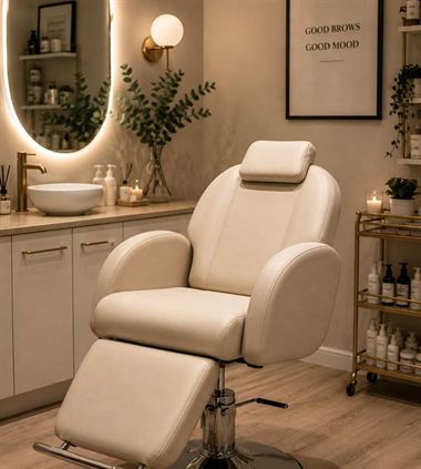 A treatment chair beside a lit mirror.