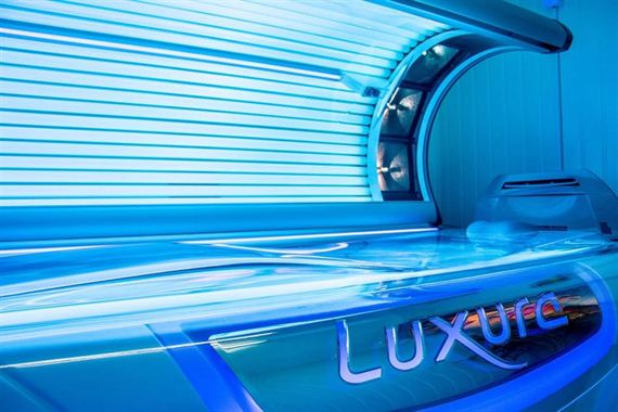 The Luxura stand-up sunbed, lit blue.